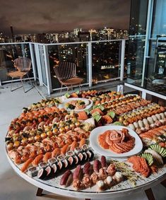 a table full of sushi and other food on top of a building at night