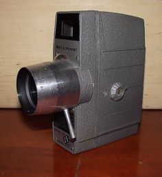 an old camera sitting on top of a wooden table