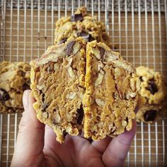 a person holding some kind of cookie on top of a cooling rack with chocolate chips and almonds