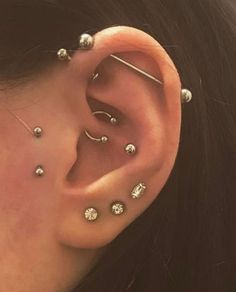 a woman's ear with multiple piercings on the top and bottom of it