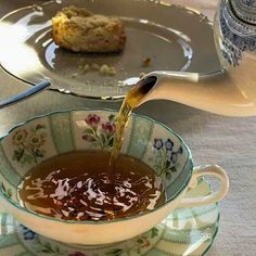 tea being poured into a cup in front of a muffin on a platter