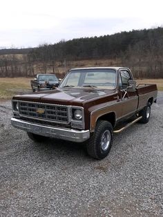 an old pickup truck parked in a gravel lot