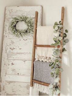 an old ladder is used as a towel rack for towels and wreaths on the wall