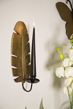 a wall mounted candle holder next to a vase with flowers and a butterfly on it