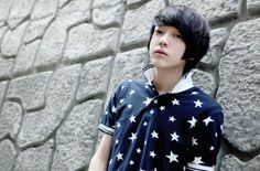 a young man standing in front of a stone wall with stars on it's shirt