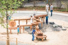 children playing in an outdoor play area with wooden benches and climbing bars, while adults watch