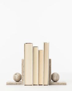 three books are stacked on top of each other in front of two rocks and one ball