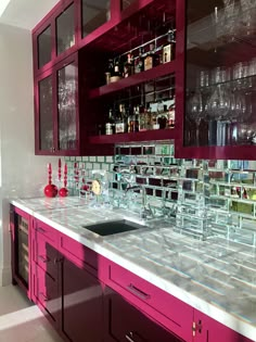 a kitchen counter with wine glasses and bottles on the back splashes in front of it