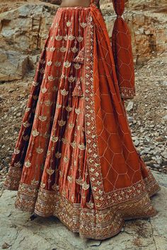 Rust full kali lehenga with floral embroidery. Paired with heavy embroidered blouse and dupatta with geometrical jaal motif work.
Component: 3
Pattern: Embroidered
Type Of Work: Nakshi
Neckline: V-Neck
Sleeve Type: Half
Fabric: Velvet, Viscose Organza
Color: Orange
Other Details: 
Nakshi, cutdana and sequins work
Side tassel tie-up lehenga
Note: The head accessory worn by the model and the cords tied to the dupatta are not for sale
Occasion: Bride - Aza Fashions Raw Silk Lehenga With Dabka Work In Traditional Drape, Floor-length Dola Silk Sharara With Intricate Embroidery, Eid Lehenga With Intricate Embroidery, Unstitched Dola Silk Lehenga With Intricate Embroidery, Embroidered Floor-length Lehenga For Eid, Raw Silk Dupatta With Intricate Embroidery, Floor-length Dola Silk Dupatta With Intricate Embroidery, Floor-length Raw Silk Dupatta With Intricate Embroidery, Eid Lehenga In Dola Silk With Dabka Work