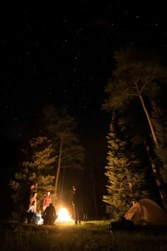 three people sitting around a campfire at night