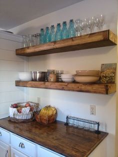 two wooden shelves above a kitchen counter with bowls and glasses on top of the shelf