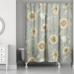 a shower curtain with sunflowers on it next to a white dresser and mirror