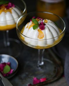 two desserts in small glass dishes with flowers on the rim and one is topped with whipped cream