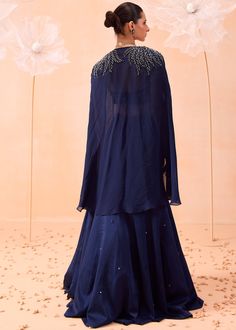 A cape style lehenga set embellished hand embroidered blouse with cutwork neckline and embroidered cape jacket. Organza Gown Designs, Cape Lehenga, Gown Indian, Organza Gown, Hand Embroidered Blouse, Embroidered Cape, Black Lehenga, Blue Cape, Organza Gowns