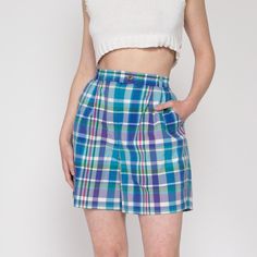 Vintage early 90s blue, green, and purple plaid shorts by Izod, with pleating at the front of the waist. Shown clipped on the model in the first two photos.  Measurements and Condition: Fits like: Labeled size 12, fits modern women's medium or up to a smaller size large Fabric: Cotton Brand: Izod Condition: Excellent Waist: 29" to 31.5" - stretches with elastic at back Hips: 45" - taken at the bottom of the zipper opening Rise: 13" Inseam: 6" Shown on a 5'8" model with measurements of 35"-26"-38", usually wears a size small to medium. See our FAQ for more info on sizing and condition ratings. Plaid Cotton Shorts For Daywear, High Waist Plaid Summer Bottoms, 90s Style Bottoms With Built-in Shorts, Retro Plaid Bottoms For Spring, Retro Plaid Bottoms With Pockets, Fitted Casual Plaid Shorts, High Waist Shorts With Pockets For Daywear, Fitted Plaid Casual Shorts, High Waist Plaid Cotton Bottoms