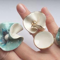 two rings with flowers on them sitting in the palm of someone's hand,