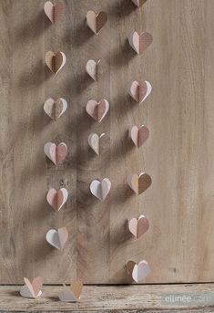 paper hearts hanging from the side of a wooden wall