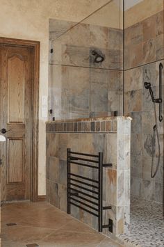 a bathroom with a walk in shower next to a wooden door and tiled flooring