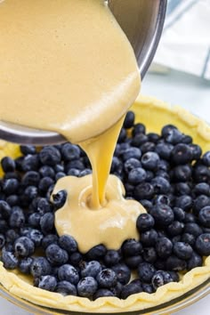 blueberries are being poured into a pie crust