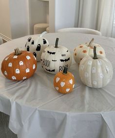 four pumpkins are sitting on a white tablecloth with black and white polka dots