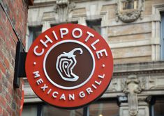 the sign for chipotie mexican grill in front of a brick building with a clock on it