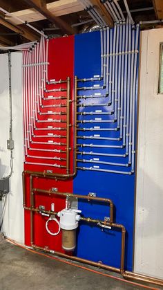 pipes are lined up against the wall with red, white and blue paint