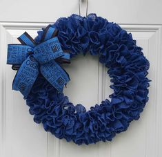 a blue wreath hanging on the front door with words written all over it and ribbons