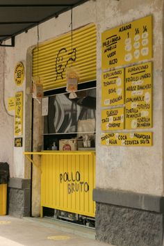 a restaurant with yellow signs hanging from the side of it's walls and windows