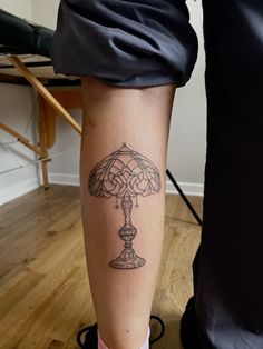 a woman's leg with a tattoo on it that has a lamp on it