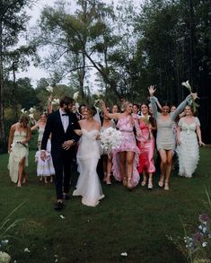 a group of people that are standing in the grass with one person wearing a tuxedo