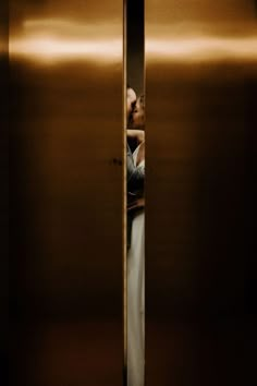 a man is standing in an elevator with his head out the door and looking at himself