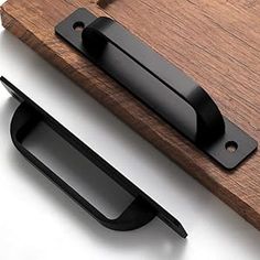 an open door handle on top of a wooden board with black handles and latches