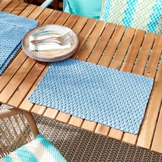 a wooden table with two place mats and a fork on top of it next to a blue towel