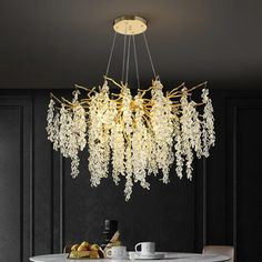 a chandelier hanging over a dining table in a room with black walls and white chairs