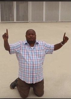 a man sitting on the ground with his hands in the air and two fingers up