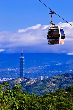 a cable car going up the side of a mountain with a city in the background