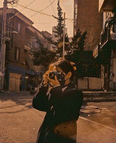 a woman taking a photo with her camera on the street in front of some buildings