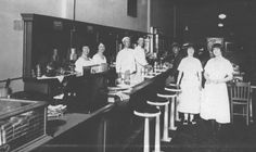 an old black and white photo of some people in a kitchen