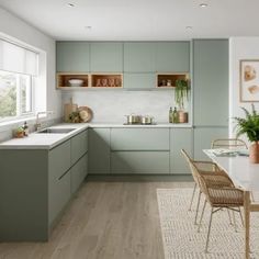 a kitchen filled with lots of green cabinets and white counter tops next to a dining room table