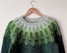 a green and white sweater hanging on a wooden hanger