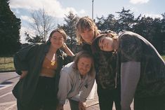 four young people posing for a photo on the sidewalk