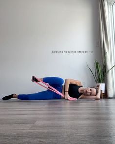 a woman is laying on the floor with a pink exercise band in front of her