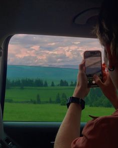 a man is looking at his cell phone while in the back seat of a car