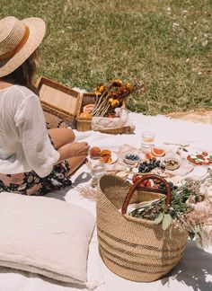 a woman sitting on the ground with her picnic basket and food in front of her