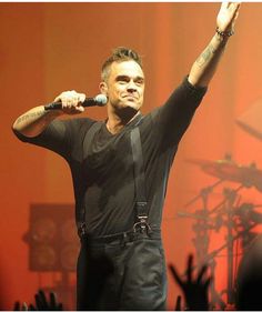 a man with his hand up in the air while holding a microphone to his ear