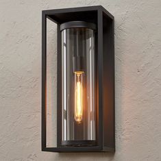 a light that is on the wall next to a white stucco wall with a black frame