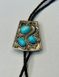 This listing is for a fantastic unisex bolo tie crafted of solid sterling silver and featuring a trio of natural sleeping beauty turquoise stones as shown in the photos. The bolo tie measures approximately 2.25" x 2" and is in wonderful condition.  Not hallmarked but acid tested as sterling.  Artist signed on the back The cord is made of genuine woven black leather and measures 36" in total length. Bolo tie is in fantastic condition. The tips are crafted of solid sterling silver as well. US ship Vintage Sleeping Beauty, Tie Crafts, Bolo Ties, Natural Sleep, Bolo Tie, Sleeping Beauty Turquoise, Turquoise Stones, Tie Accessories, Suit And Tie