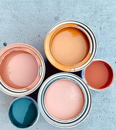 four different colors of paint sitting on top of each other next to each other in cans