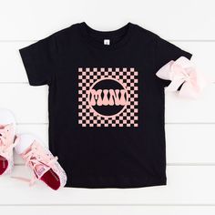 Looking for a cute tee for your kids? We have the perfect Checkered Mini graphic tee addition to their closet! Also available in toddler tees. Cute Black Unisex T-shirt, Cute Unisex Black T-shirt, Cute Black T-shirt With Graphic Design, Playful Streetwear T-shirt With Logo Print, Cute Black T-shirt With Screen Print, Playful Logo Print T-shirt For Streetwear, Cute Black T-shirt With Text Print, Cute Pre-shrunk Black T-shirt, Cute Black Pre-shrunk T-shirt