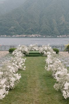 an outdoor ceremony setup with white flowers and greenery in front of the water's edge